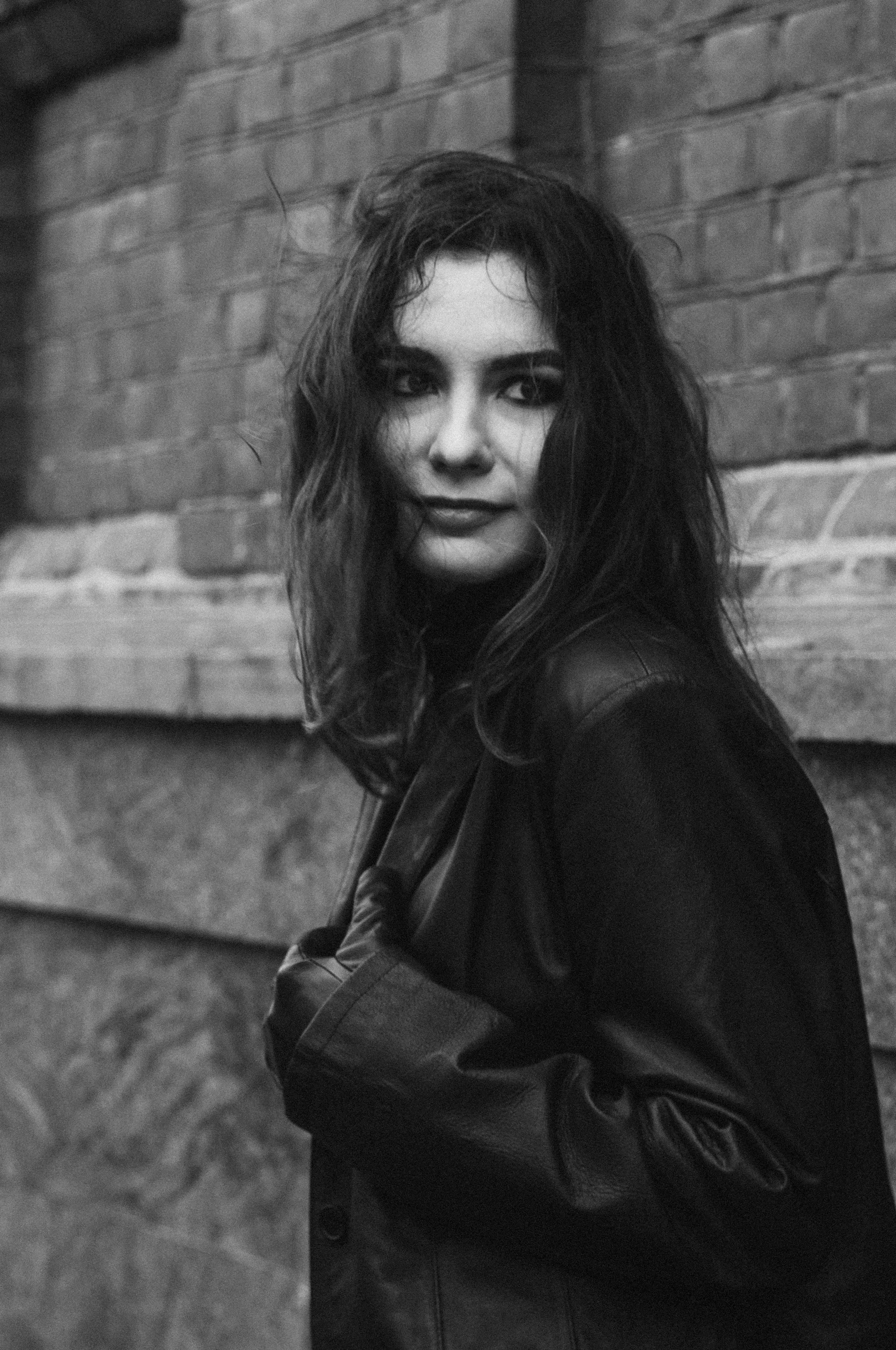 Woman in Black Jacket Standing Beside a Wall · Free Stock Photo