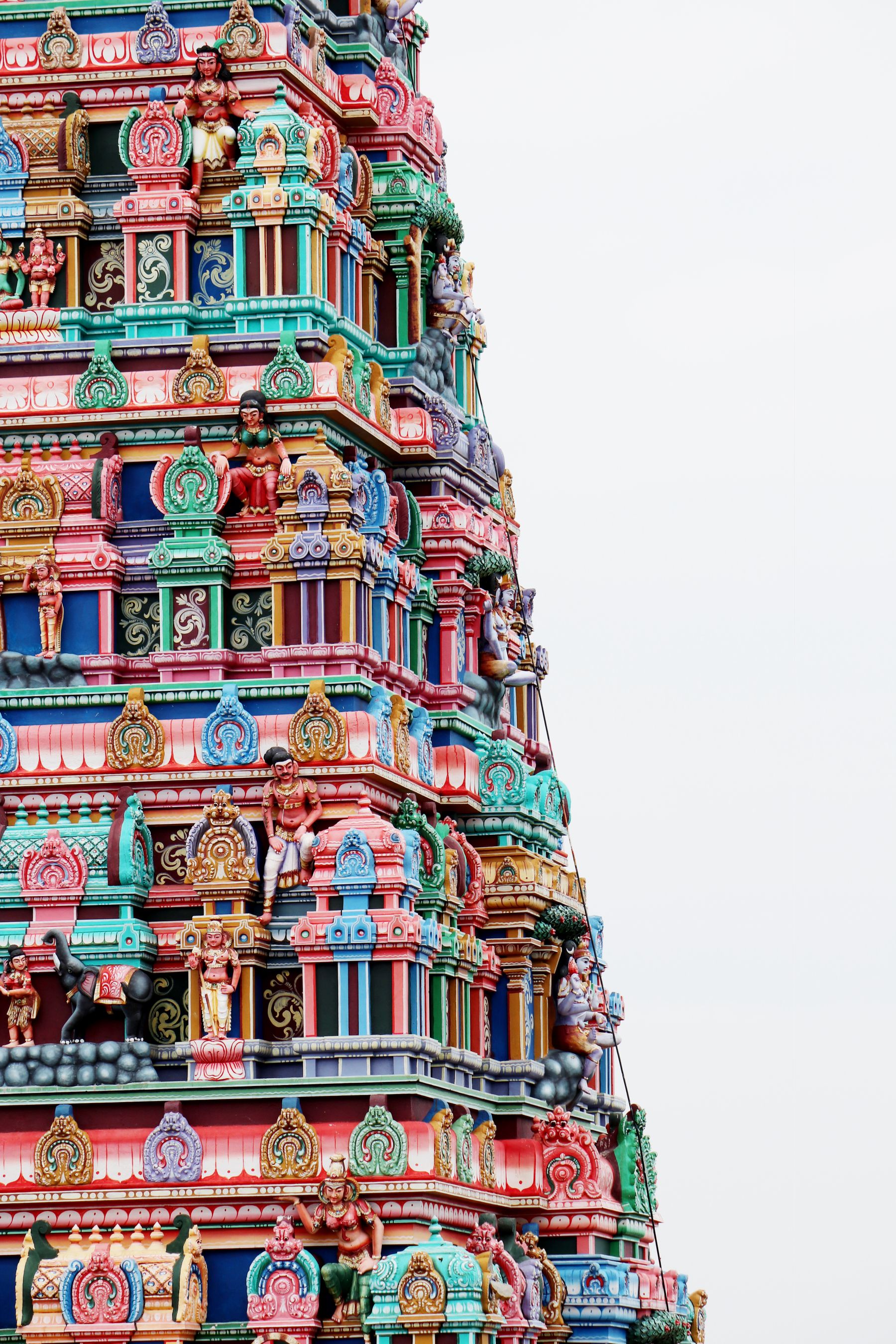 A painted temple gateway tower crowded with sculpted figures rising above Madurai