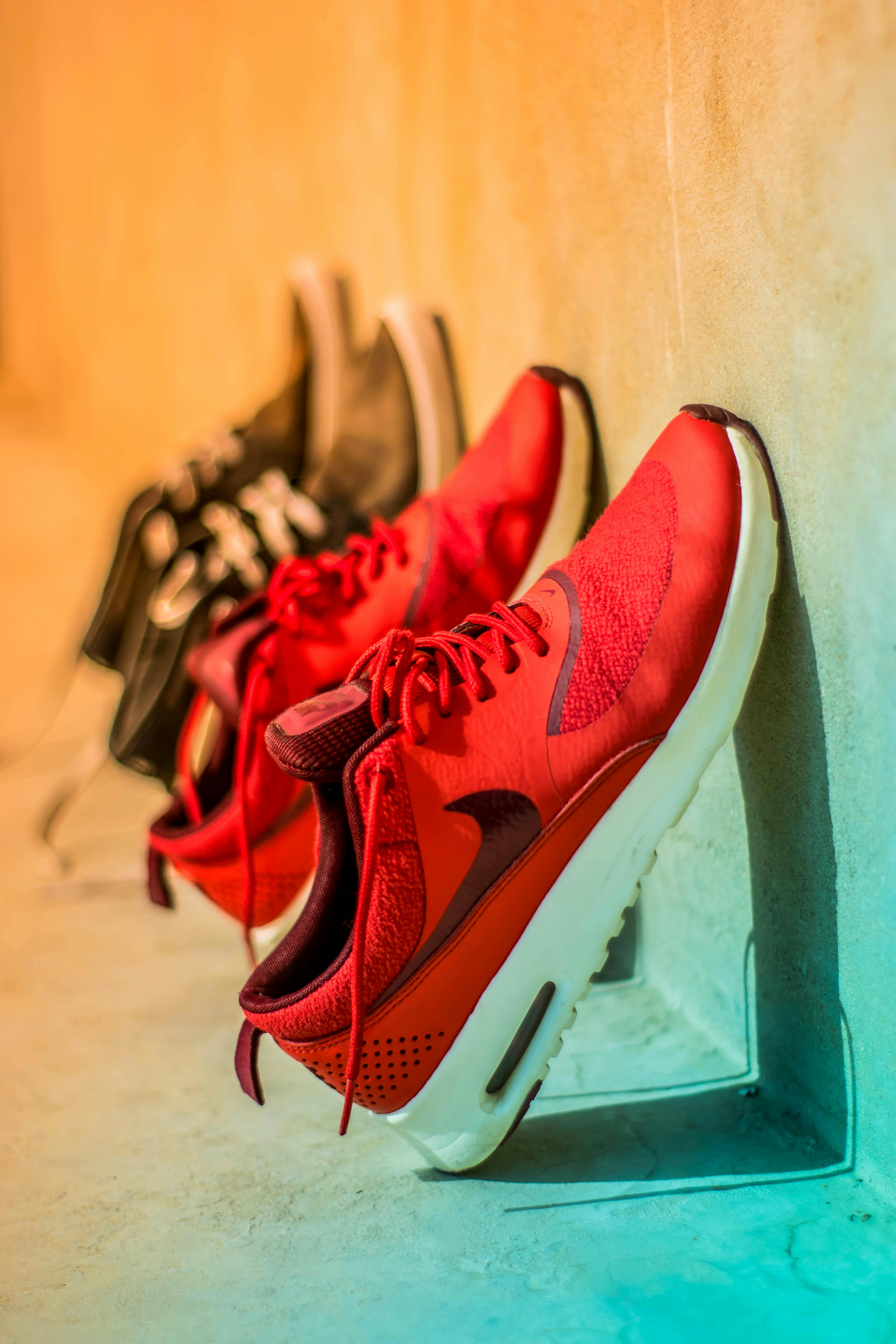 focus photography of pair of red nike running shoes