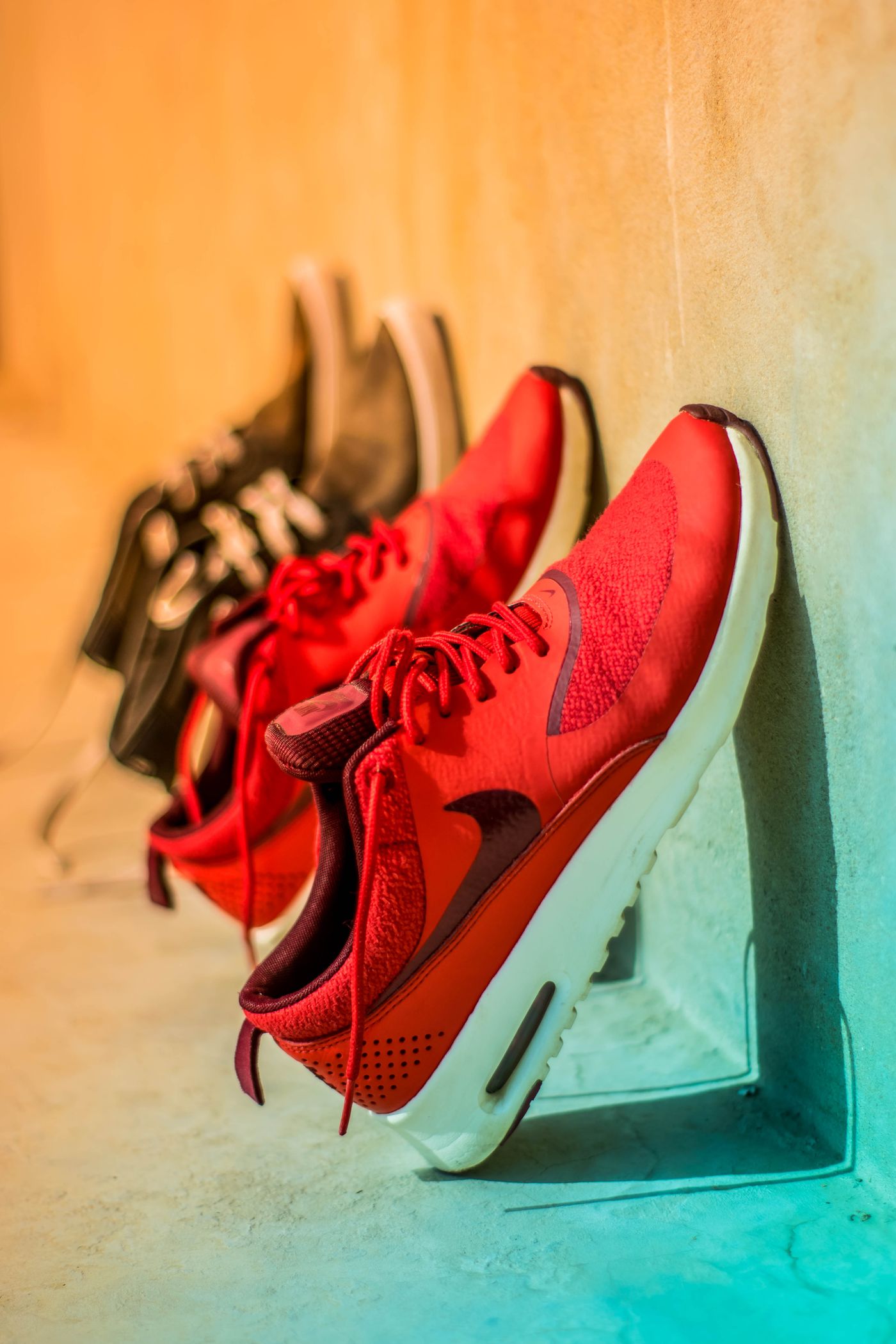 Zapatillas rojas exclusivas alineadas en exposición contra una pared cálida