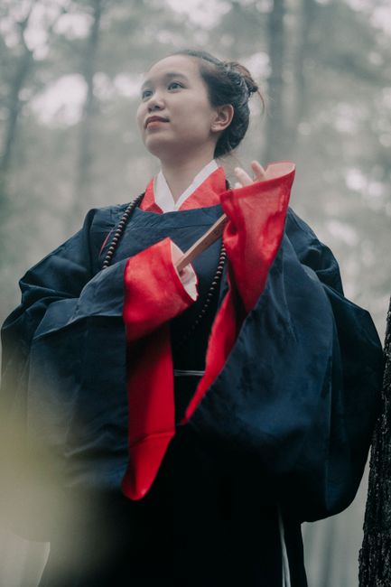 Asian woman wearing traditional clothing in a misty forest, creating an ethereal mood.