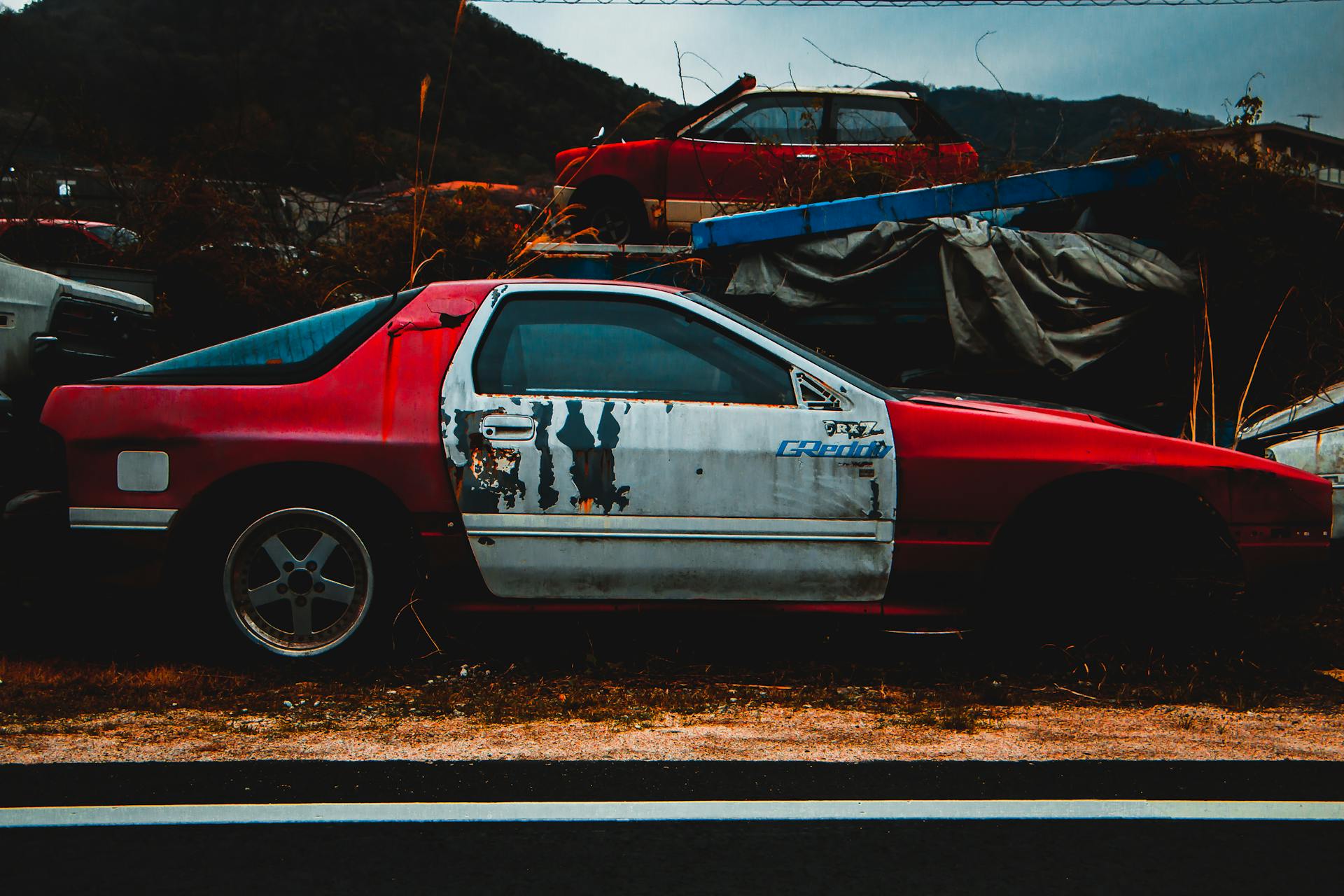 Rusty old sports car abandoned outdoors in Takahashi, Japan, exuding vintage decay.