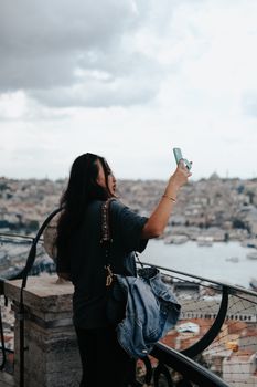 A woman captures a stunning view of Istanbul from a city overlook, showcasing urban beauty.