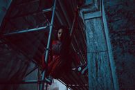 Woman in Red Costume Holding on a Scaffolding