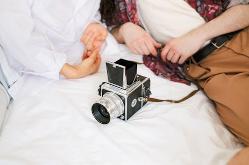 A Shot of an Analog Camera in Front of a Couple Lying on a Bed 