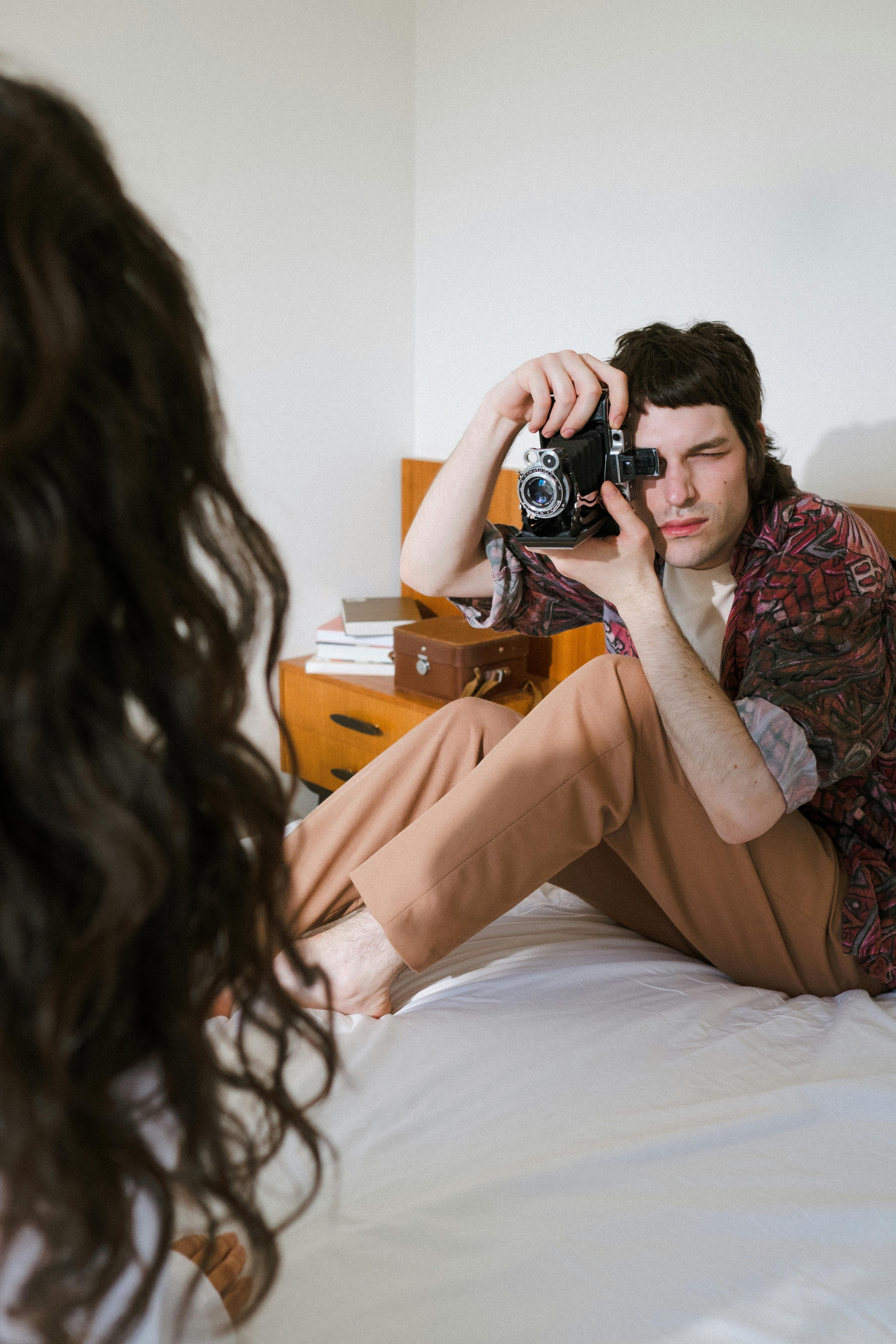 a male filming a female with an analog camera