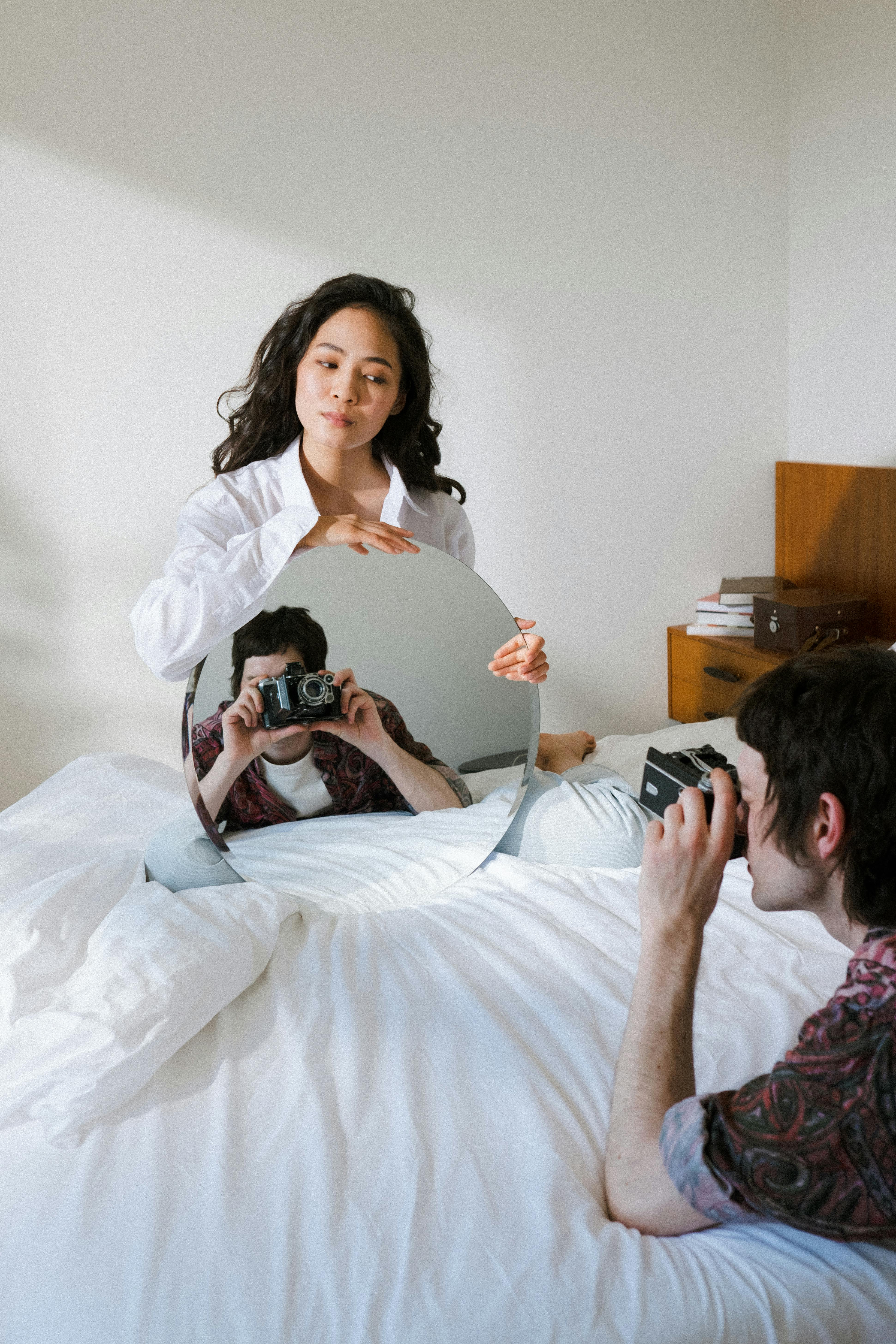 a male filming with an analog camera and female holding a mirror while photoshoot