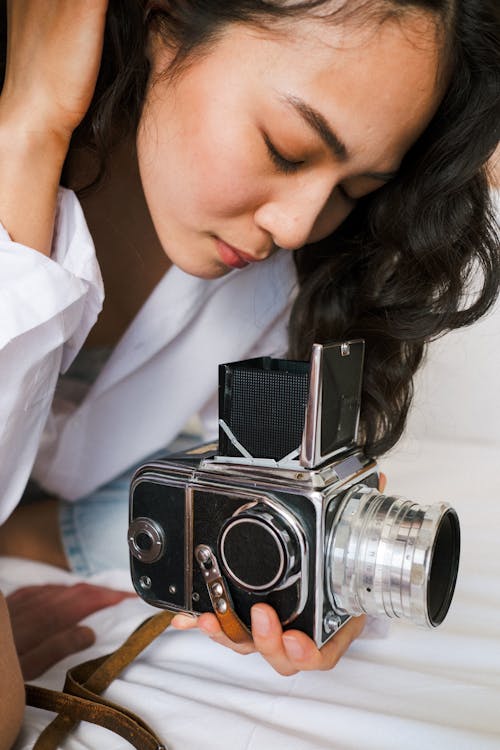 A Side View of a Female Looking Down on an Analog Camera 