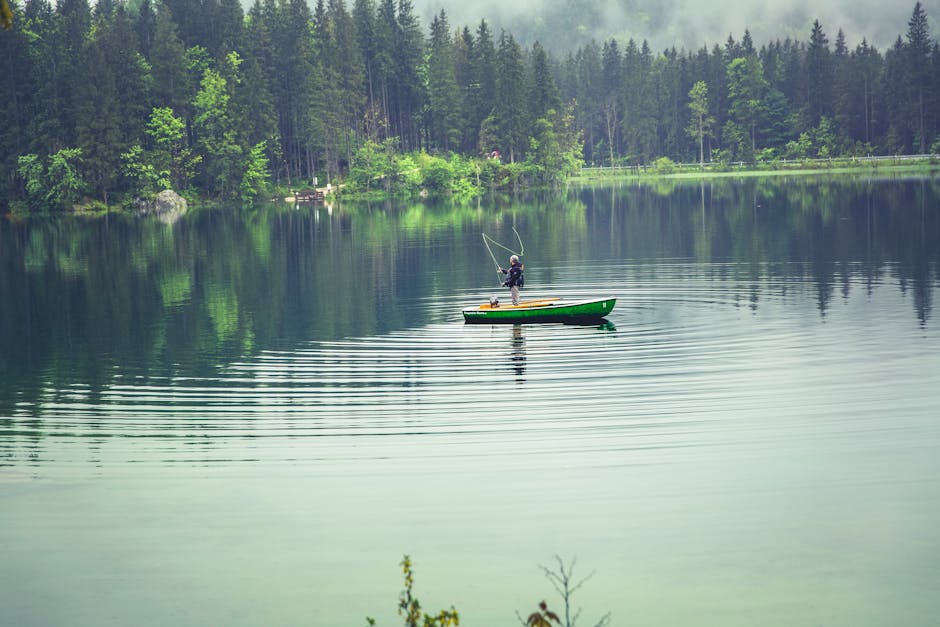 Person on Green Boat Fishing on Body of Water