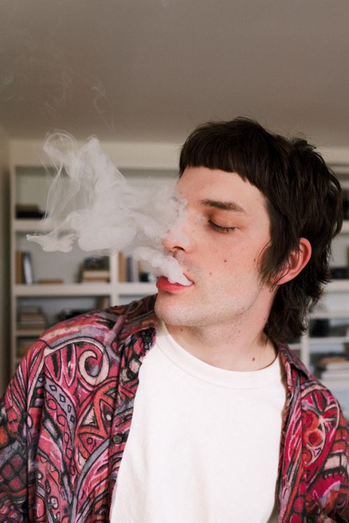 Free A young adult exhaling smoke in an indoor setting, highlighting modern lifestyle choices. Stock Photo