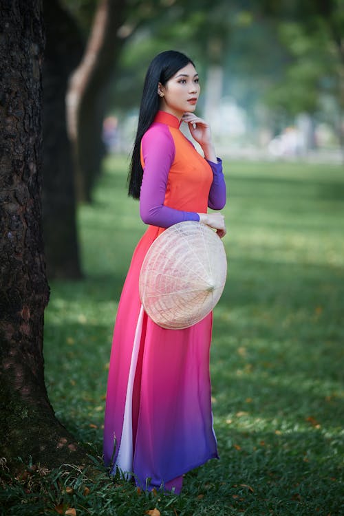 Photo of a Woman with an Asian Conical Hat Wearing a Colorful Dress