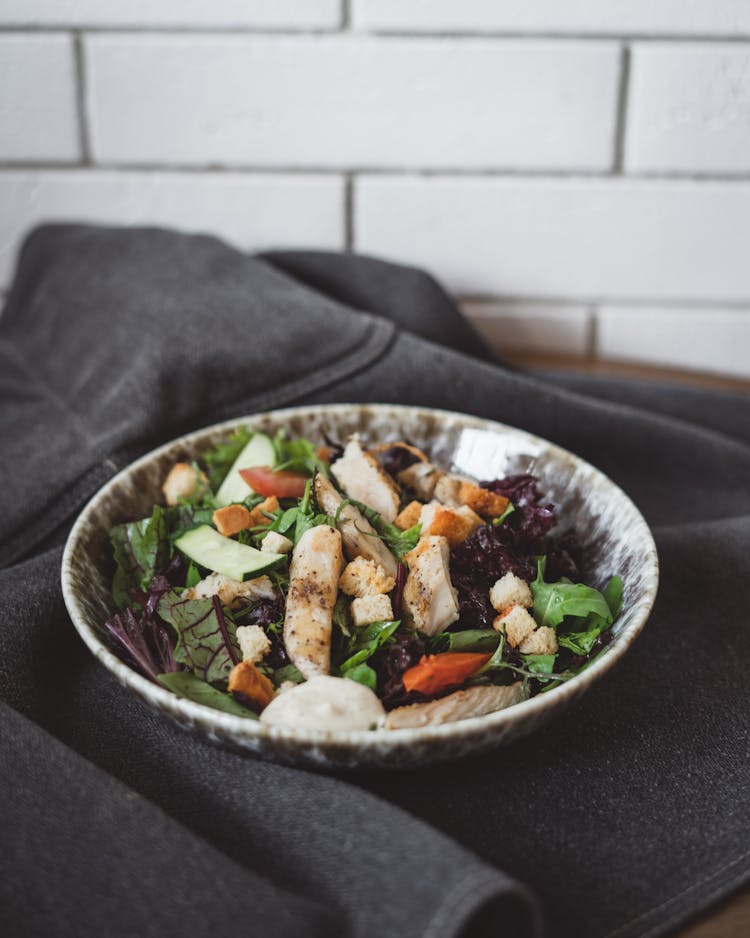 Caesar Salad Presented On Plate On Gray Fabric