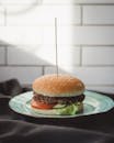 Hamburger Served on Ceramic Plate Presented on Gray Fabric