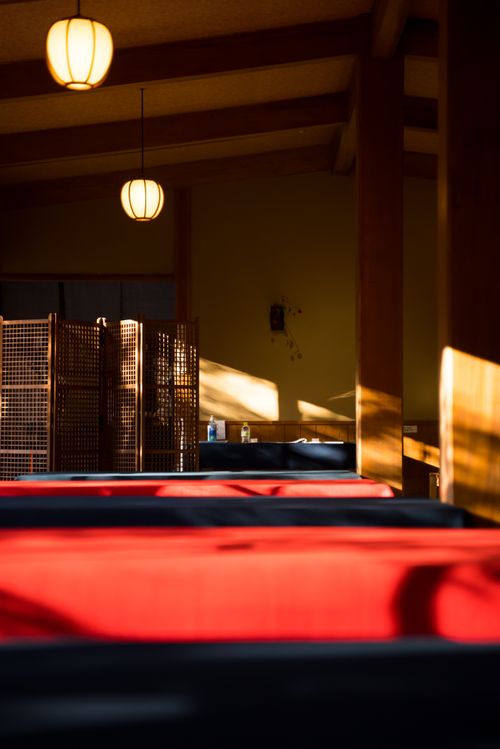Free A serene Japanese-style room with warm lighting, red cushions, and wooden decor in Kyoto. Stock Photo