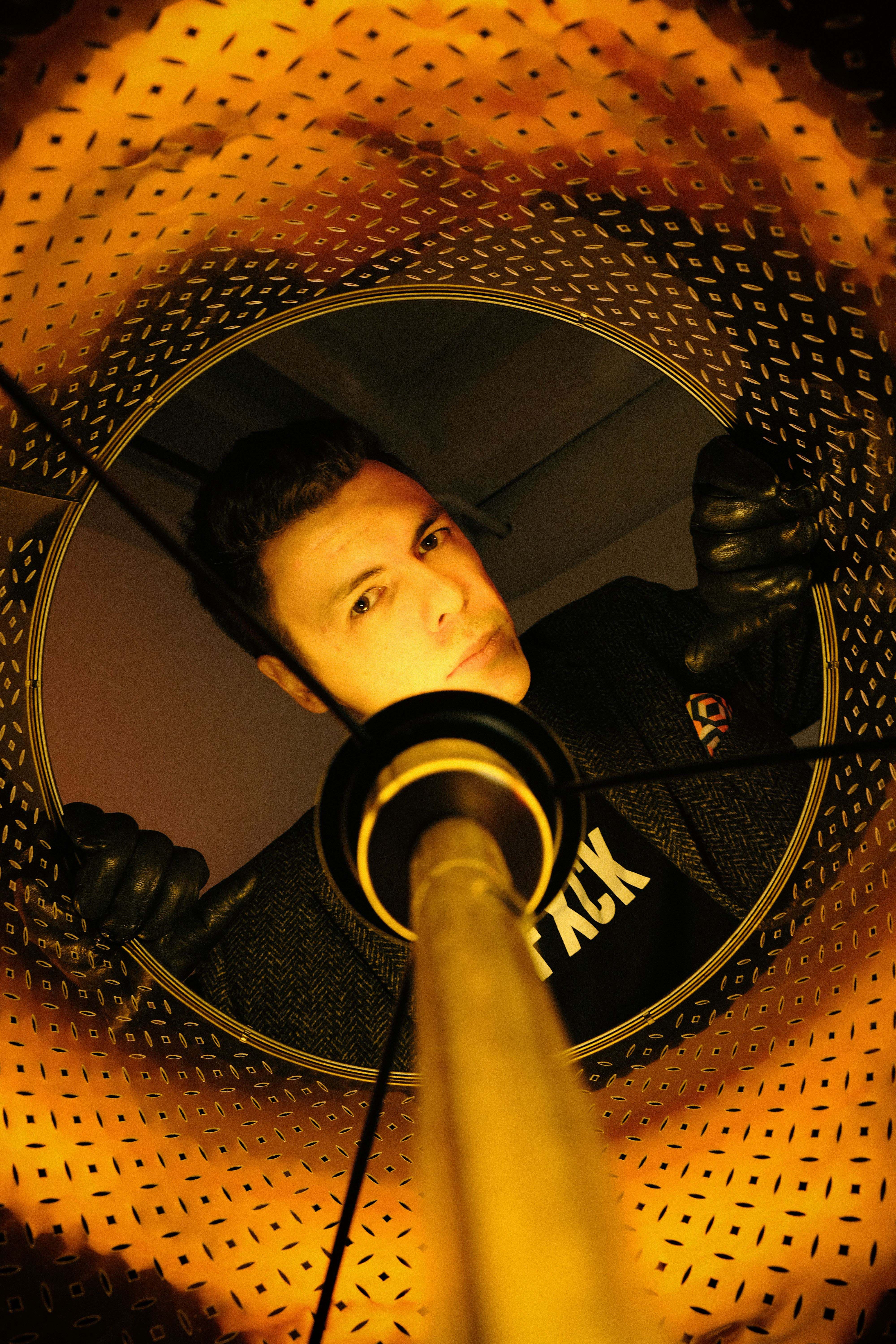 Artistic shot of a man inside a washing machine drum with orange lighting.