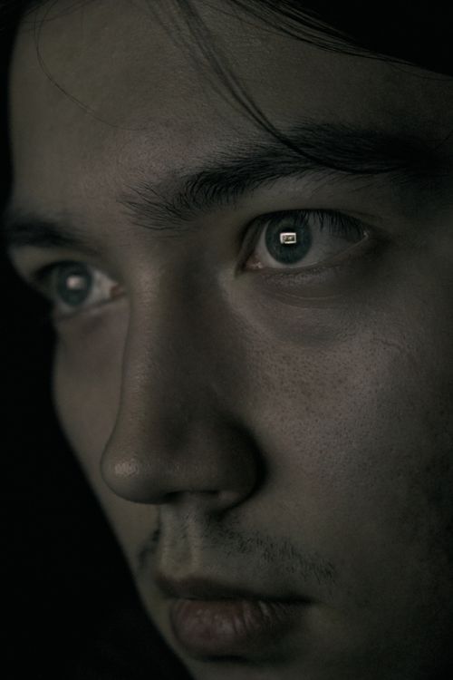 Free Close-up portrait of a male with screen reflection in eyes, conveying introspective mood. Stock Photo