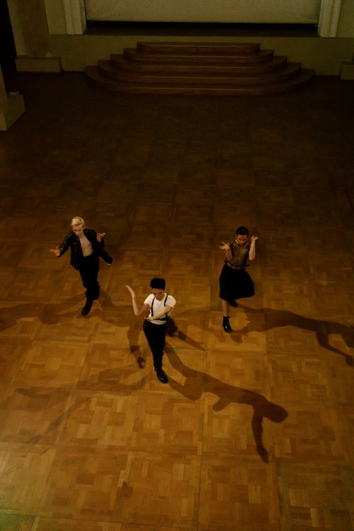 Free Aerial view of three dancers performing in a vintage ballroom setting with wooden floors. Stock Photo