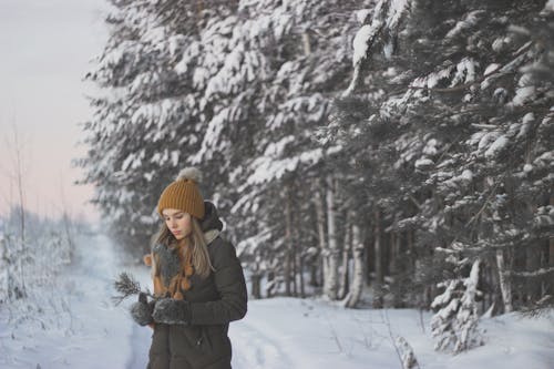 A Woman Wearing a Winter Clothes Standing Near the Snow-Covered Trees