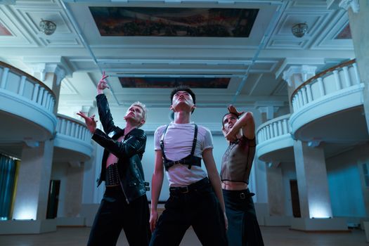 Three dancers in a grand indoor space showcasing eclectic fashion and expressive moves.