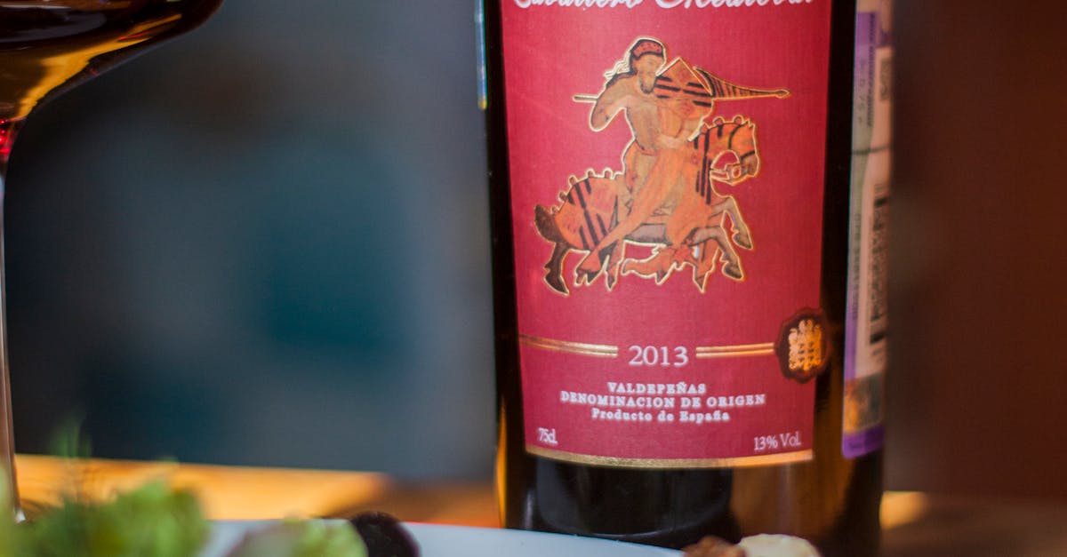A bottle of red Spanish wine next to a platter of assorted cheeses and grapes on a wooden table.