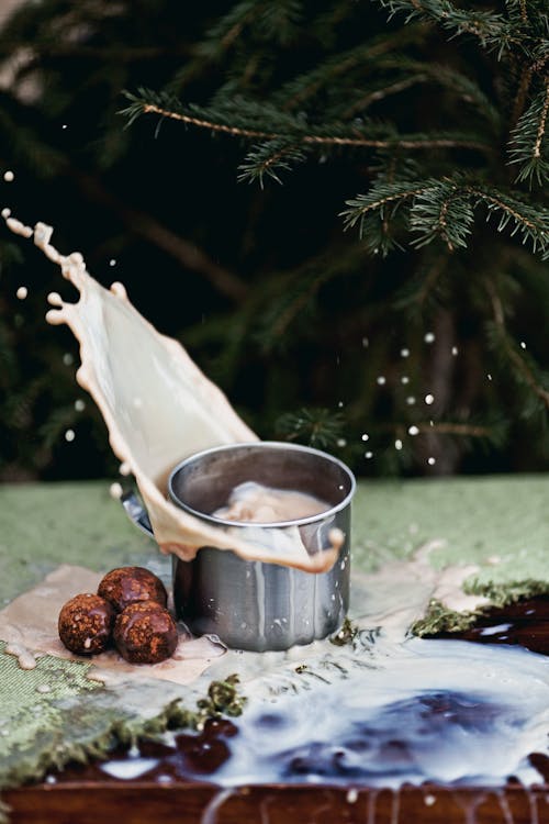 A Splash of Milk From a Pot and Chocolate Balls Pastry Next to It 