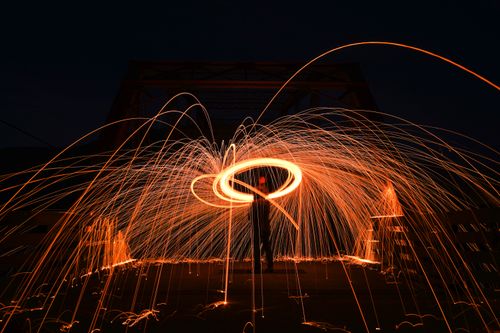 Free Dynamic steel wool photography creating sparks and patterns at night on a bridge, exhibiting light trails. Stock Photo