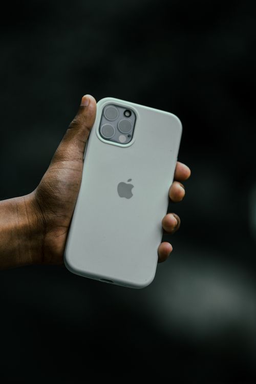 Free Close-up of a hand holding a sleek smartphone with a dark background. Stock Photo