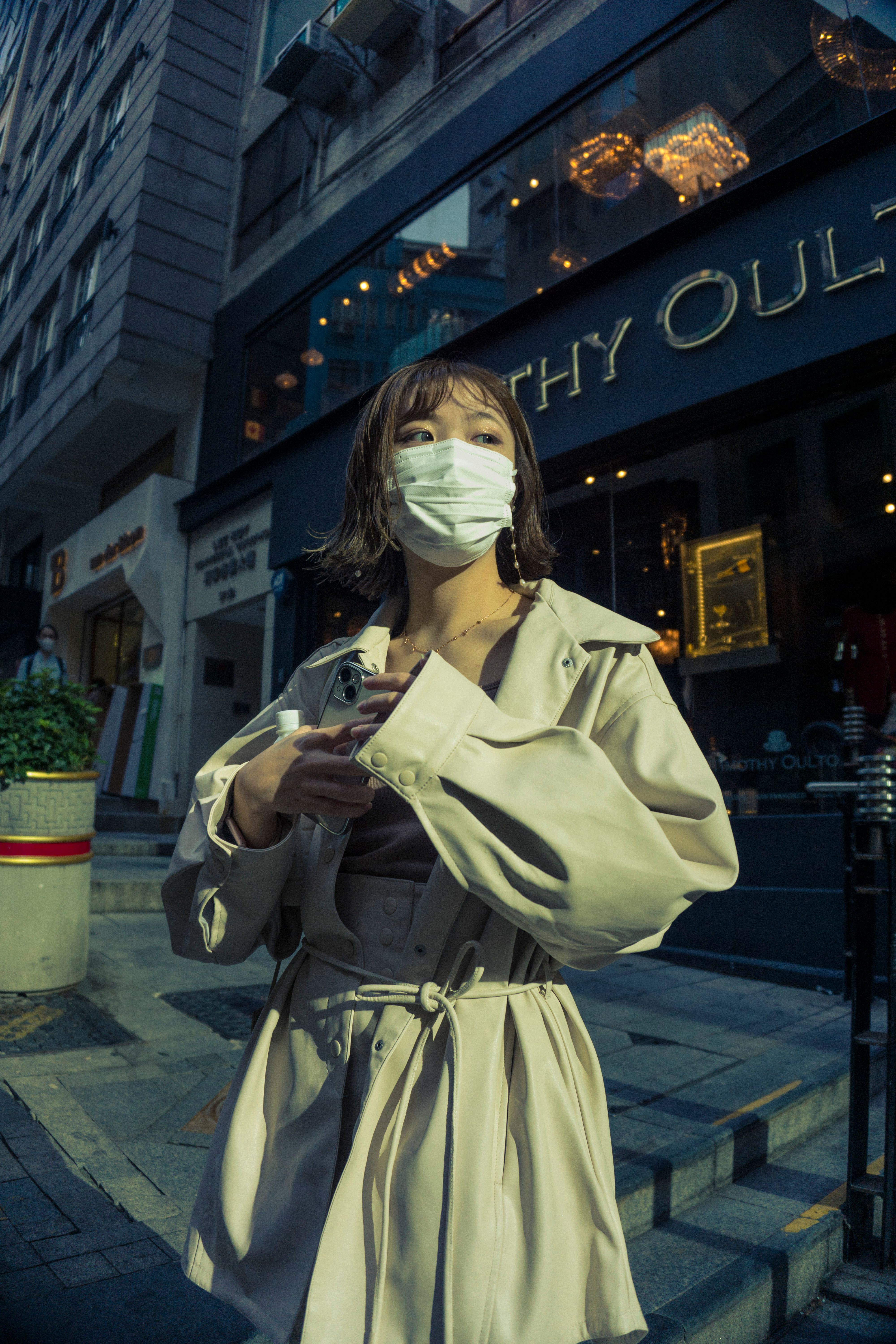 Fashionable woman in a mask walking city streets, embracing new normal in Hong Kong.