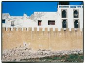 A historic wall with worn architecture under clear blue skies in Morocco.