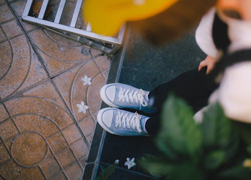 Free Photo of a Person's Shoes Near White Flowers Stock Photo