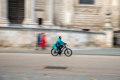 Man in Blue Jacket Riding a Bicycle on the Road