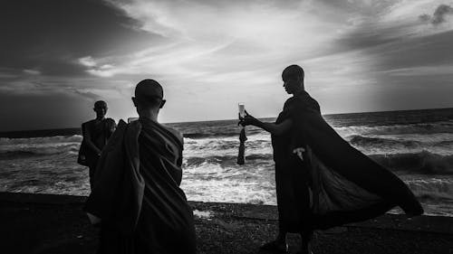 Greyscale Photography of Three Monks Near Ocean