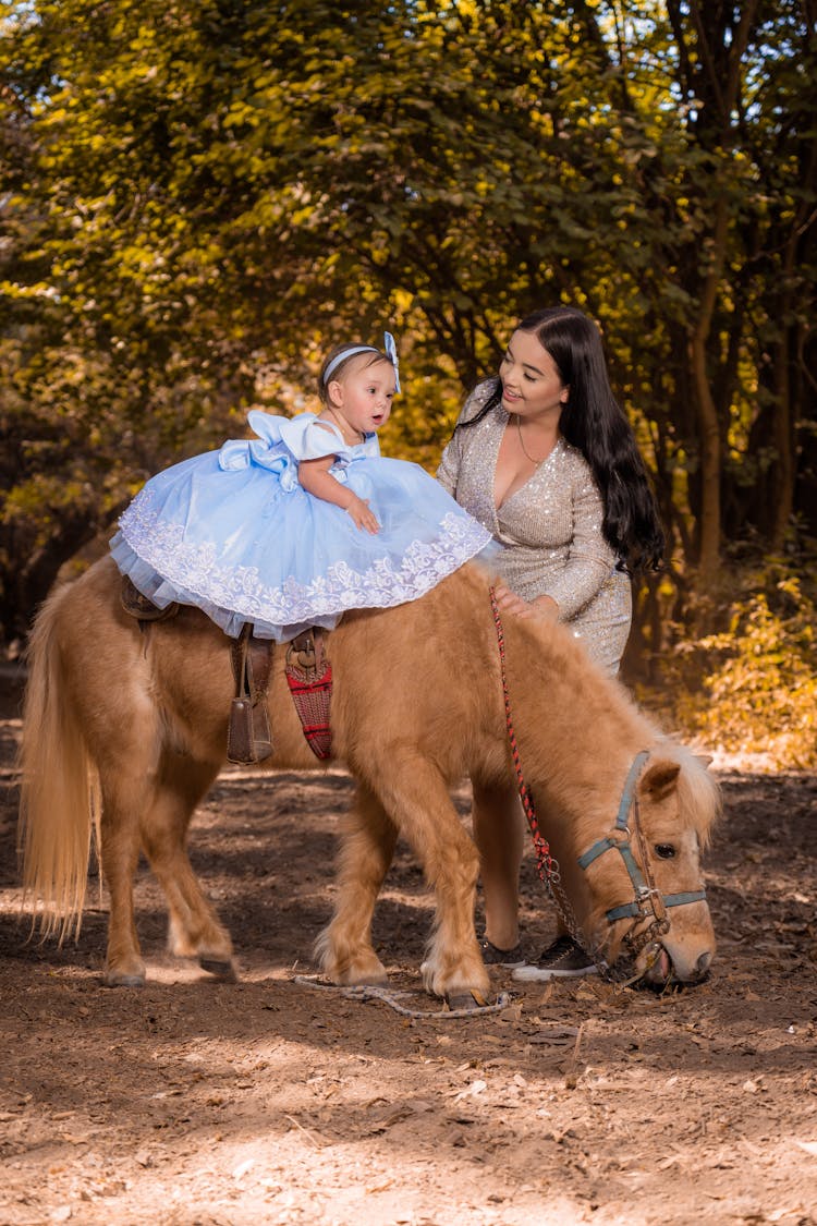 A Girl Wearing A Blue Dress Riding A Pony