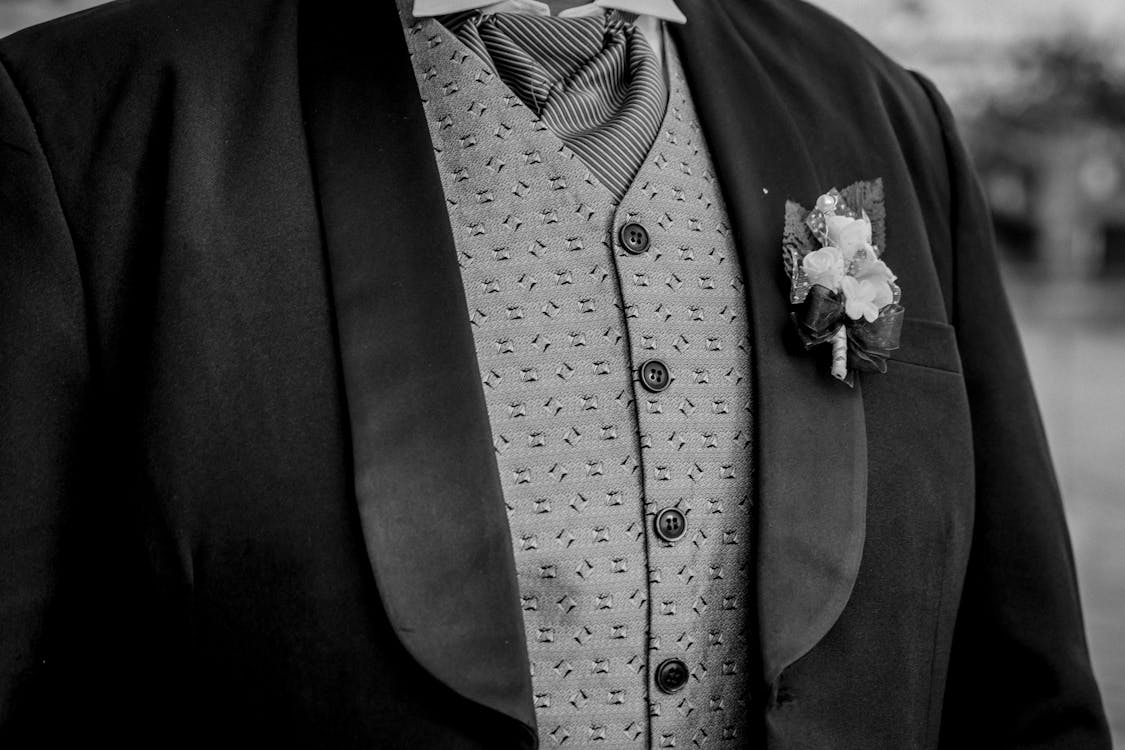 Grayscale Photo of a Flower Brooch Pinned on a Suit
