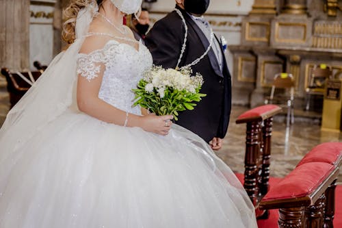A Bride and Groom Wearing Face Masks Standing at the Altar 