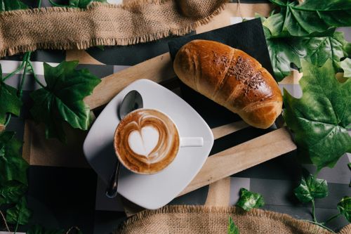 Free Top view of a cappuccino with latte art and a croissant on a rustic table in Naples, Italy. Stock Photo