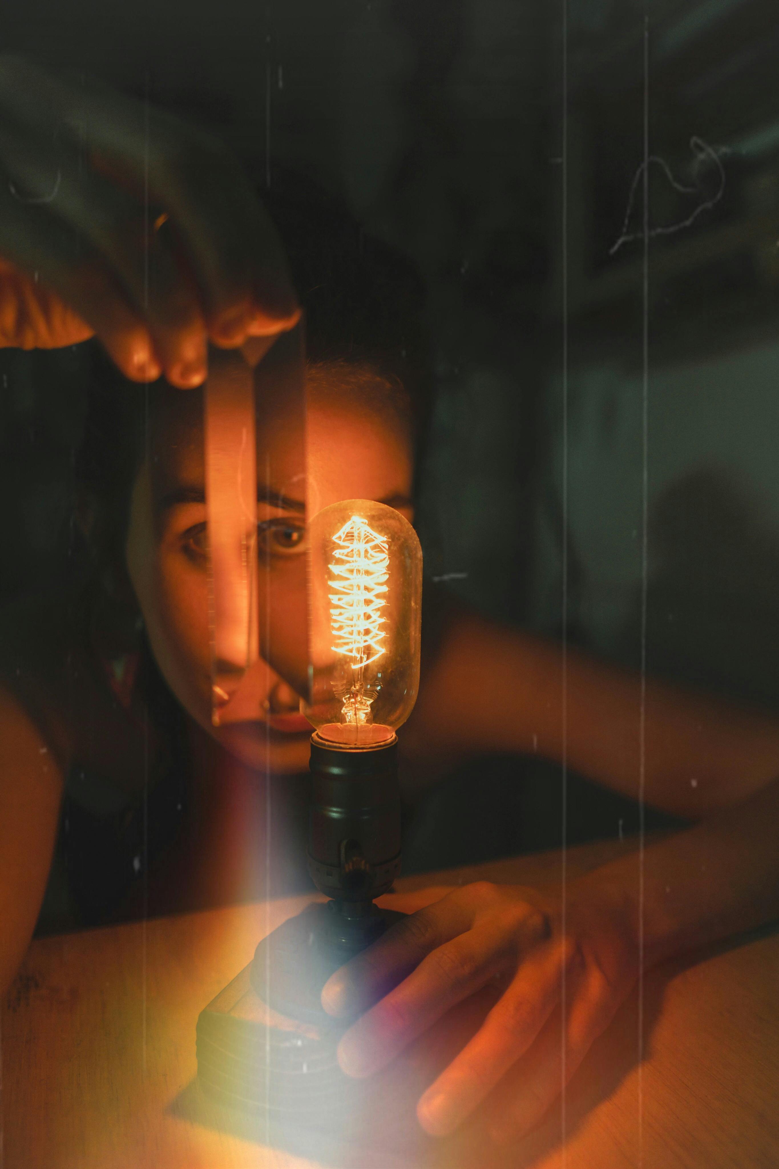 Artistic photo of a woman holding a glowing vintage lightbulb, creating a warm atmosphere.
