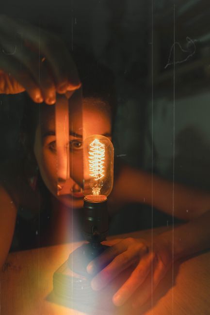 Artistic photo of a woman holding a glowing vintage lightbulb, creating a warm atmosphere.