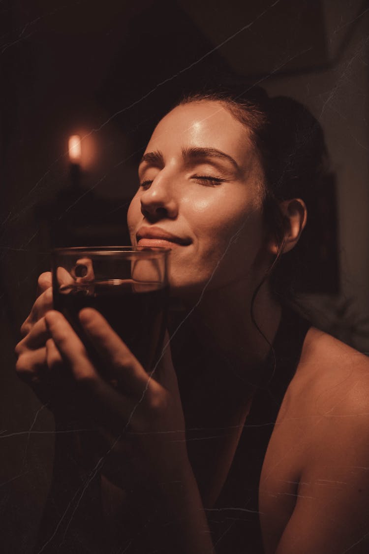 A Woman Smelling A Cup Of Coffee