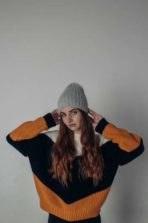A Woman in Orange and Black Sweater and Gray Beanie