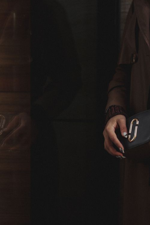 Free Stylish crossbody bag held by a person, reflected in a window. Stock Photo
