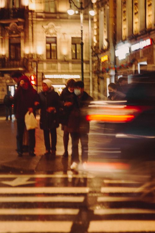 Free Blurred city street scene at night with pedestrians crossing, capturing motion and urban atmosphere. Stock Photo