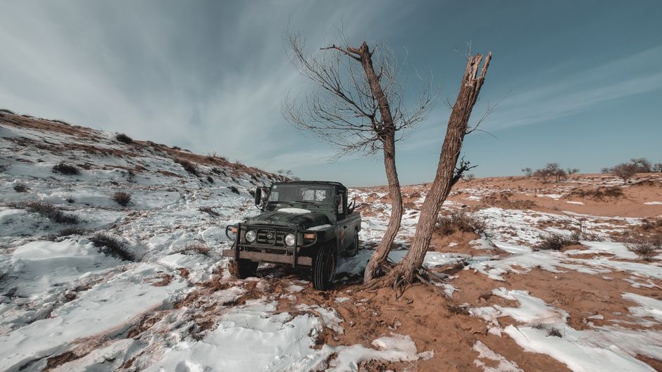 A rugged SUV parked in a snow-covered desert, showcasing winter adventure travel.