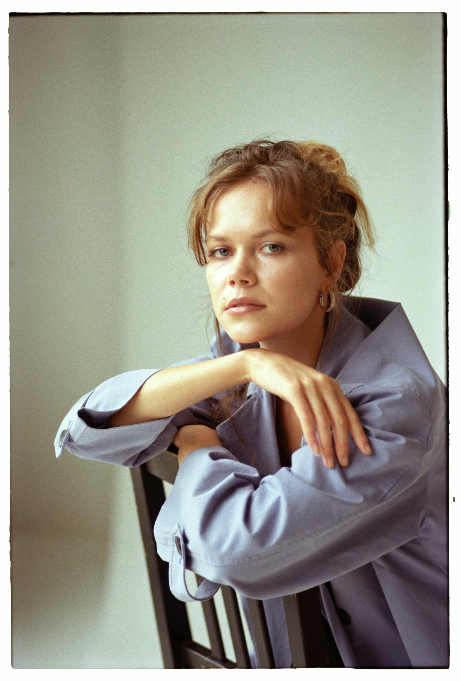 Elegant portrait of a woman seated on a chair, exuding a serene and contemplative demeanor.