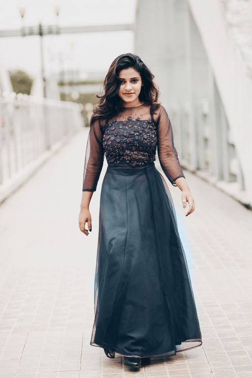 Free South Asian woman in elegant dress walking confidently on a modern bridge. Stock Photo
