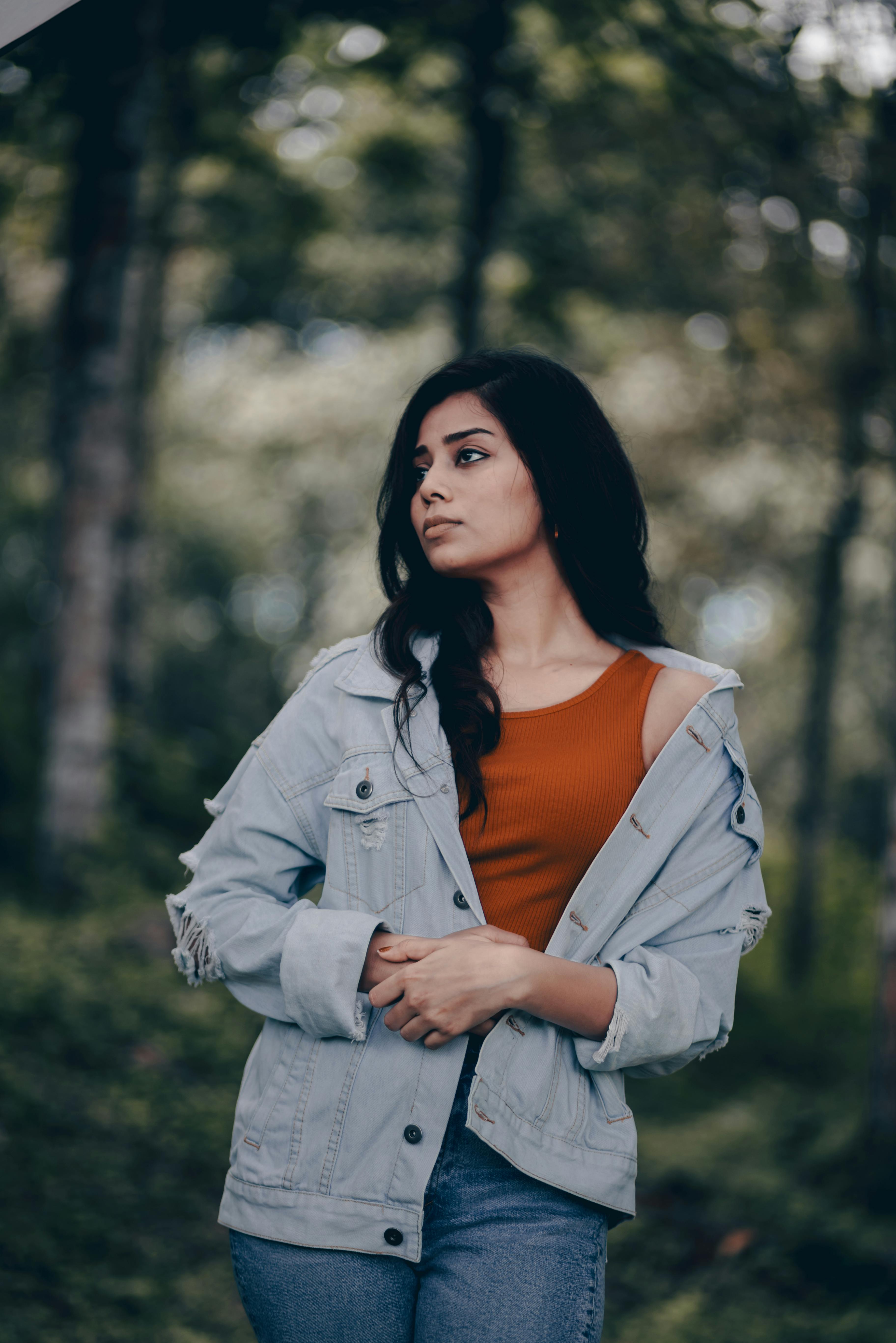 Young brunette girl with long flowing hair dressed in jeans jacket poses  holding her hands on her Stock Photo by leikapro