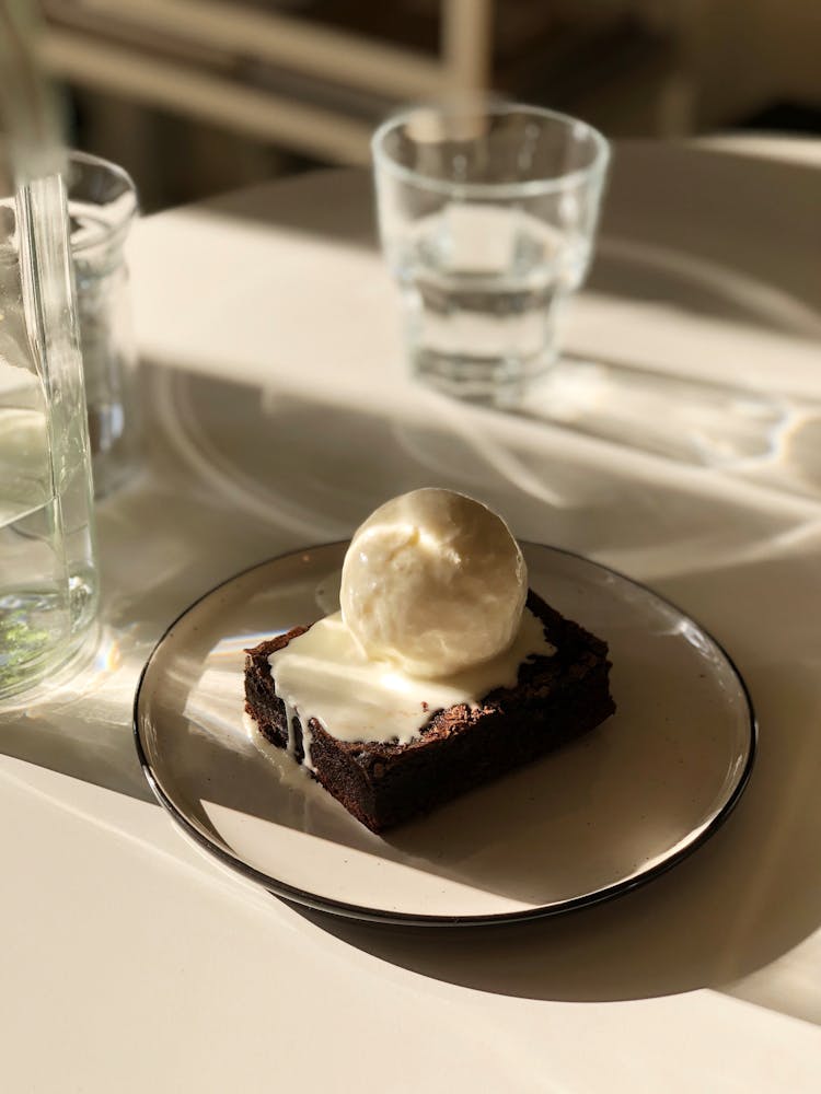 Snowball Dessert On Slice Of Brownie Covered With Cream