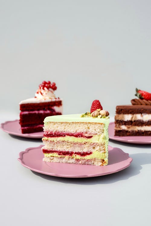 Free Pieces of Various Birthday Cakes Presented on Pink Ceramic Plates Stock Photo