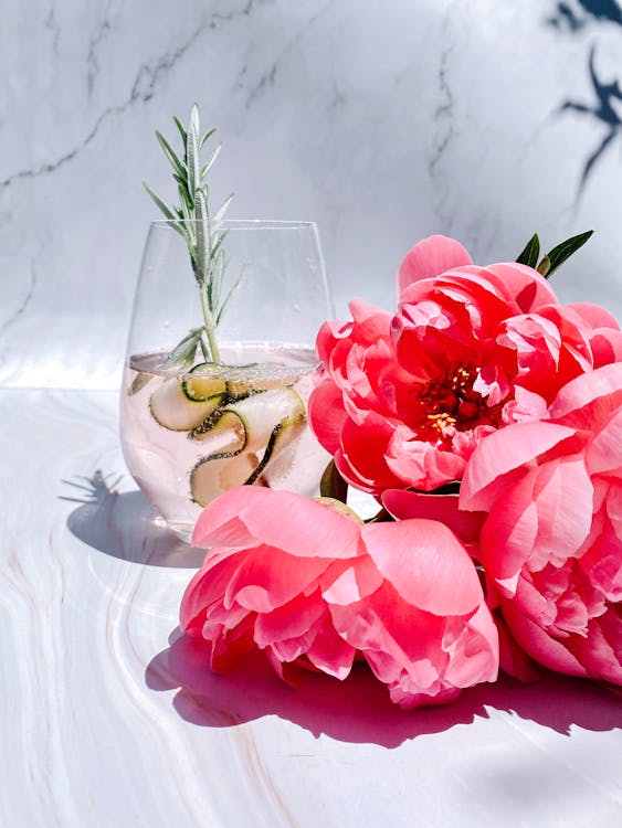 Free Cocktail in Glass Next to Pink Artificial Flowers Stock Photo