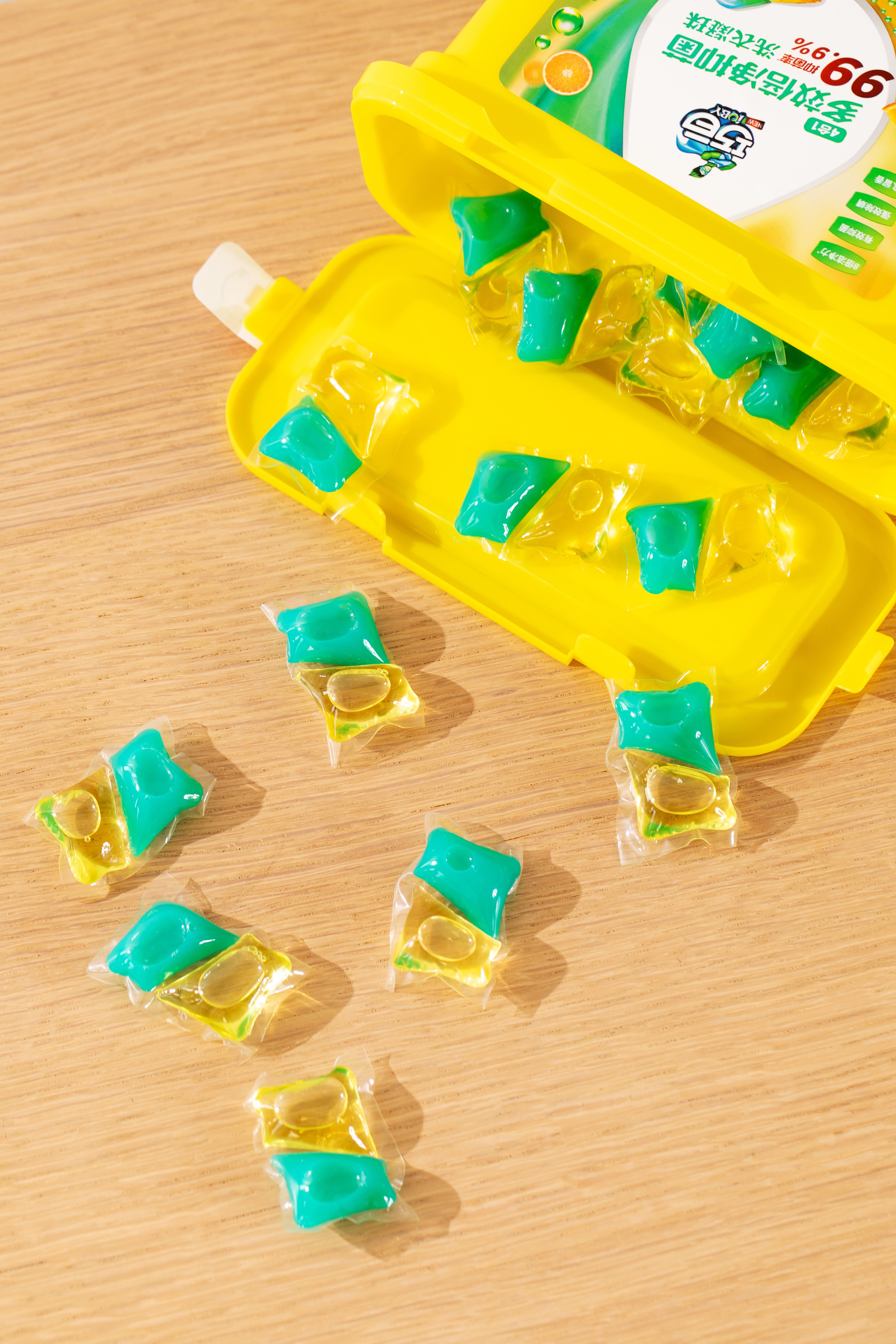 Colorful laundry detergent pods scattered on a light wooden surface with opened packaging.